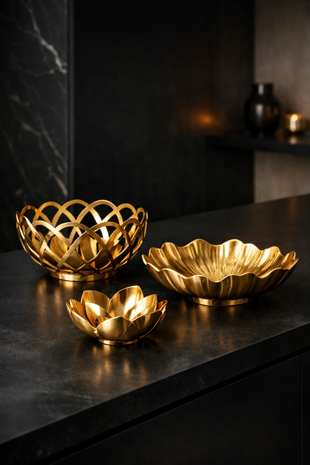 Three gold decorative bowls on a black kitchen counter.